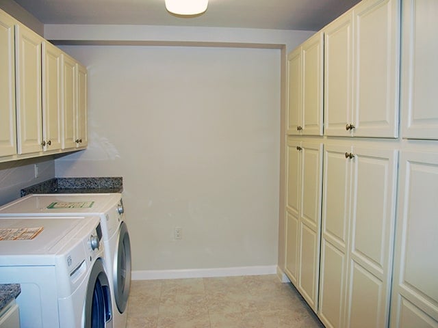 laundry room with off-white utility cabinets and a white front-loading washer and dryer in a Linden Ponds apartment in Hingham, MA