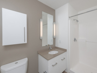 a modern white single bath vanity with quartz vanity top in an Ames Shovel Works apartment in North Easton, MA