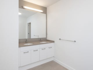 a modern white double bath vanity with quartz vanity top in an Ames Shovel Works apartment in North Easton, MA