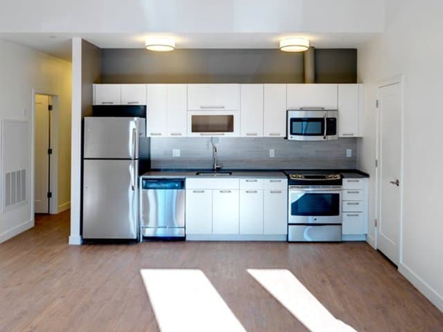 modern white kitchen cabinets with quartz countertops and stainless steel kitchen appliances in an Ames Shovel Works apartment in North Easton, MA