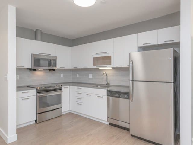 modern white kitchen cabinets with quartz countertops and stainless steel appliances in an Ames Shovel Works apartment in North Easton, MA