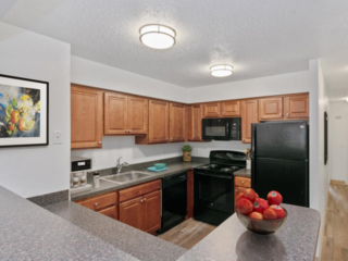 a kitchen in Stockbridge Court Apartments featuring medium-finish stained cabinets, laminate countertops and black appliances in Springfield, MA