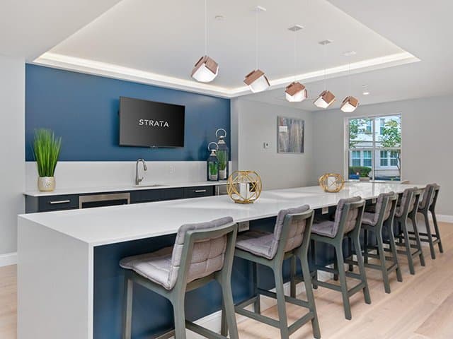 a community space with cabinets, countertops, stools and a TV at Strata apartments in Malden, MA