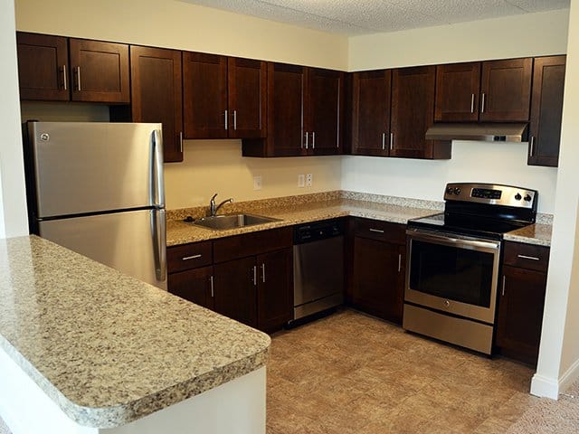 an autumn brown kitchen with laminate countertops and stainless steel appliances in a Weymouth Commons apartment in Weymouth, MA